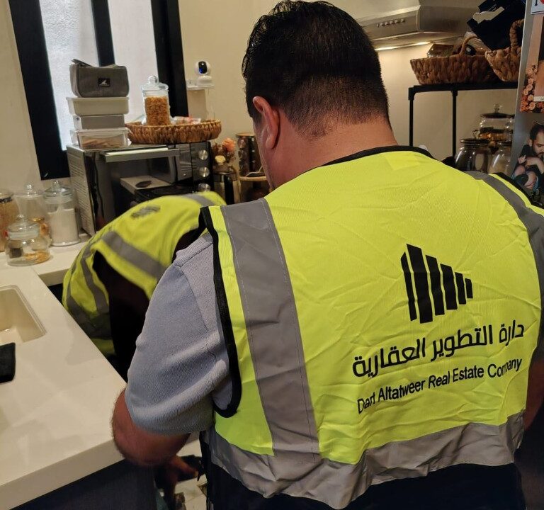 فنيان من دارة التطوير العقارية بستيرات السلامة أثناء صيانة داخل مطبخ حديث ضمن إدارة أملاك بالرياض